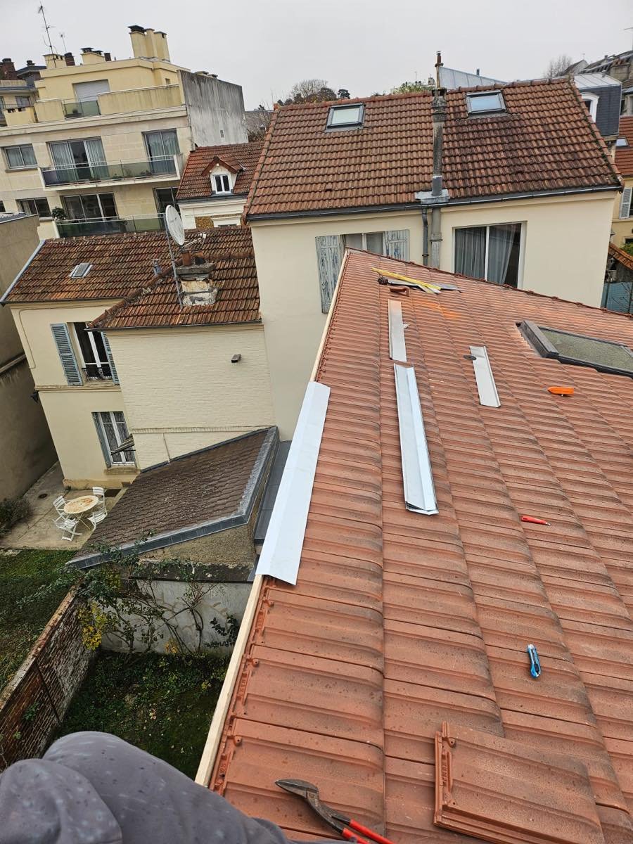 Pose des tuiles neuves en cours avec les rives métalliques