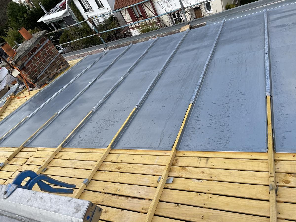 Premières feuilles de zinc posées entre les tasseaux, en partie haute du versant