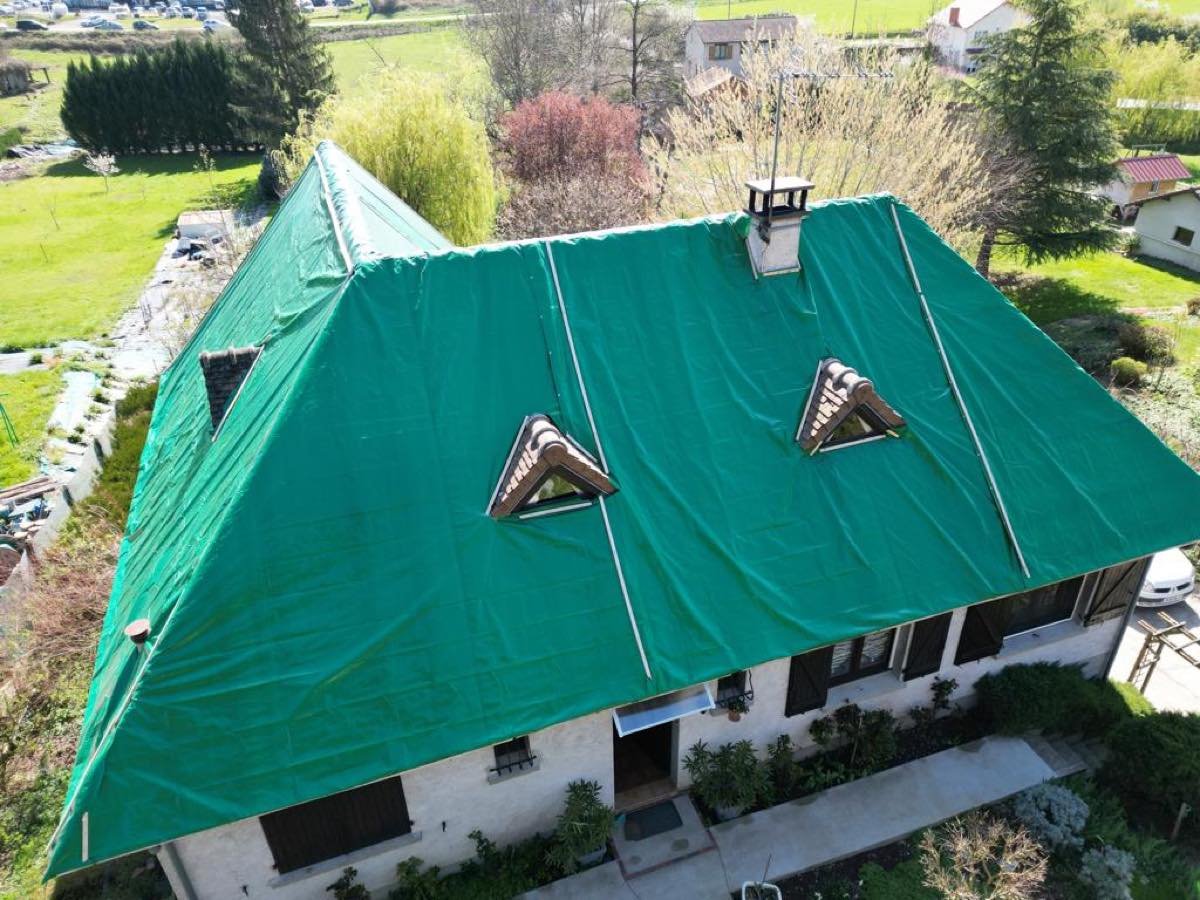 Vue aérienne d'une maison dont toute la toiture est bâchée