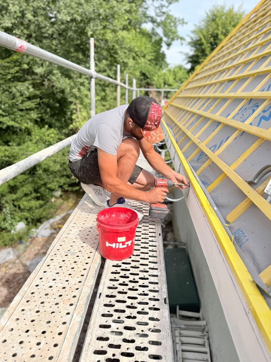 Couvreur fixant la gouttière en pied de toiture